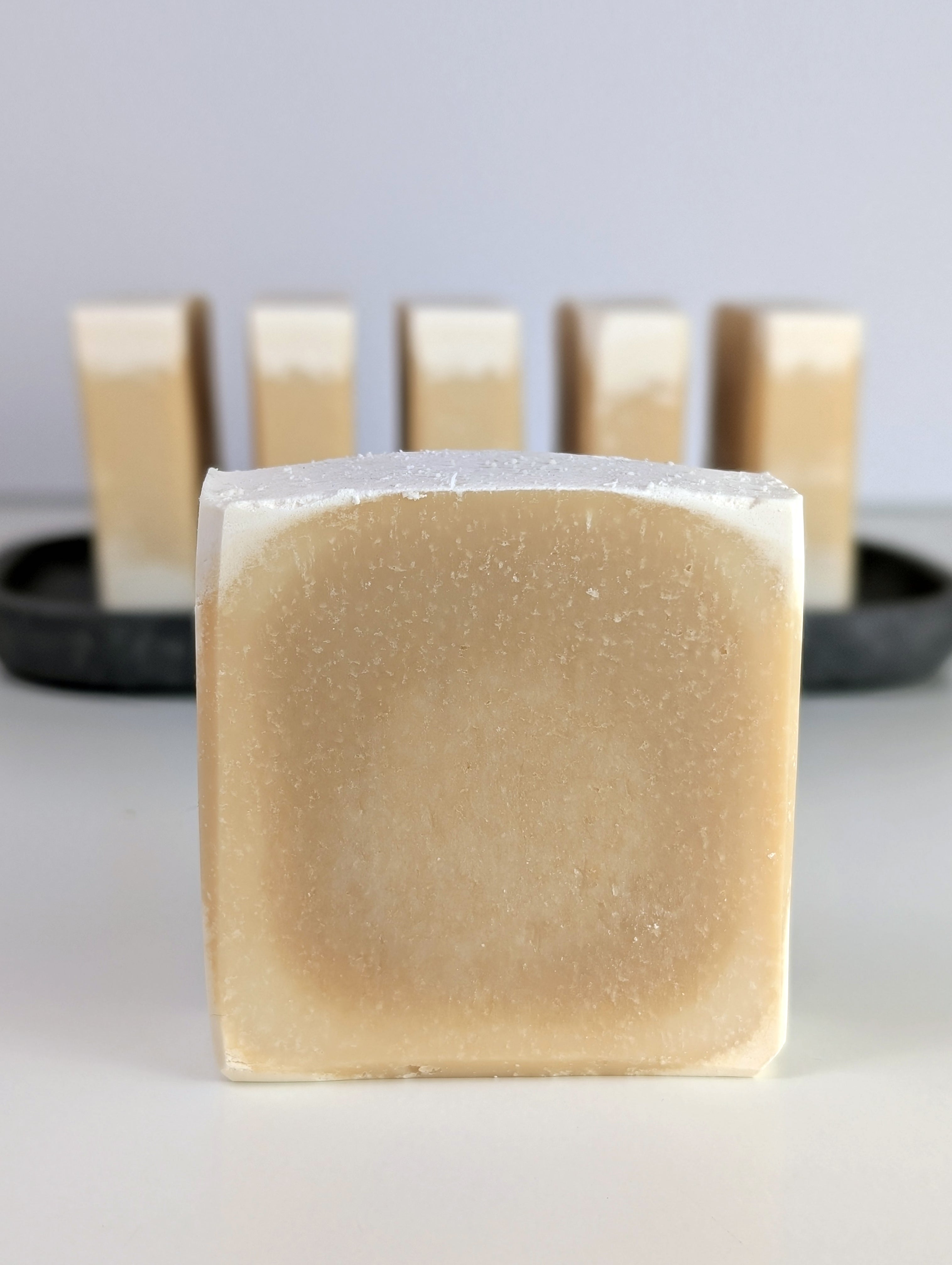 Single bar of soap in the foreground with a white background.