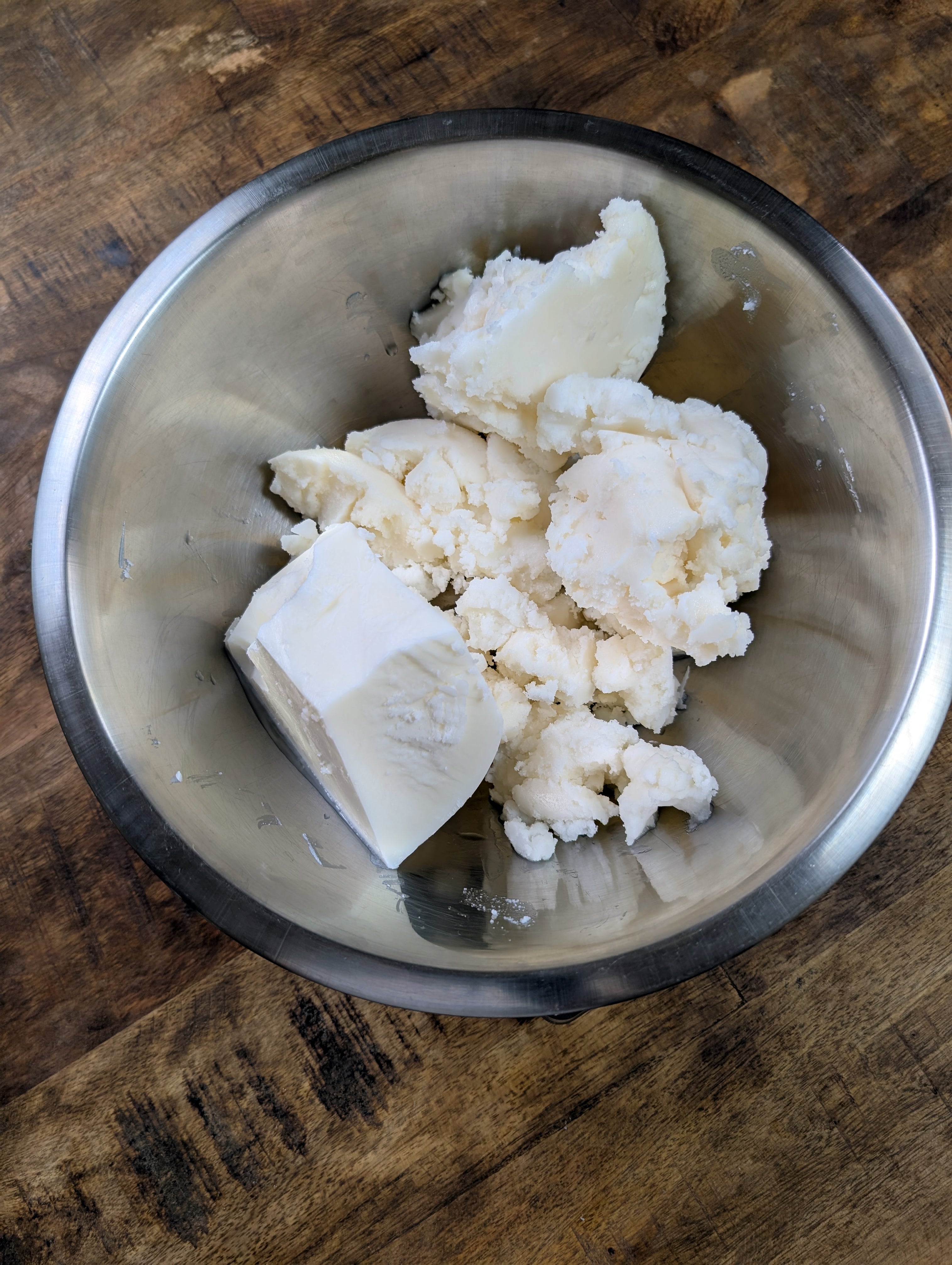 Crumbed beef tallow in a metal bowl on a dark wooden surface